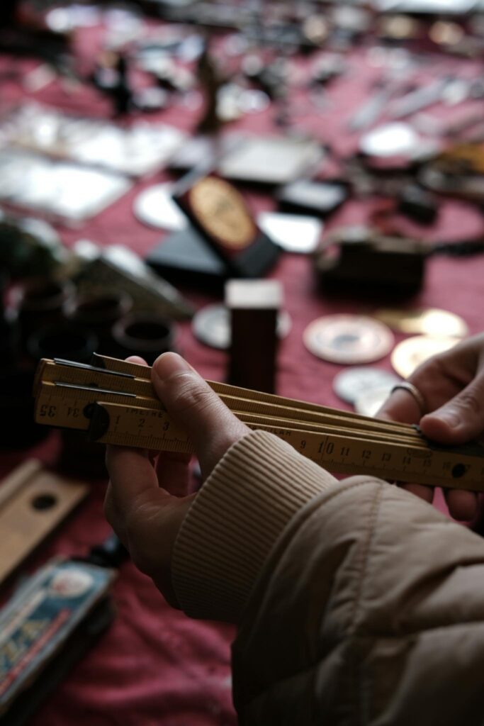 Close-up of hands holding a vintage ruler at an outdoor antique market.